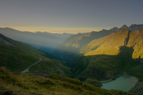 Berglandschaft mit Alpensee, sanfte Hügel im Abendlicht.