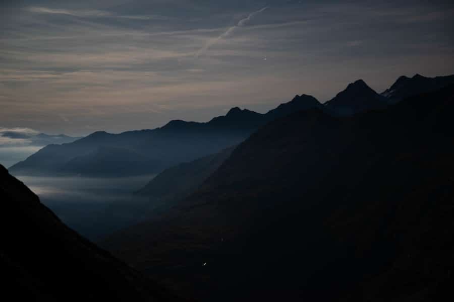 Nächtliche Bergsilhouetten mit Nebel unter einem klaren Himmel.