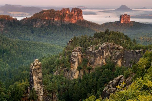Blick auf Sandsteinfelsen im Elbsandsteingebirge, umgeben von Wäldern.