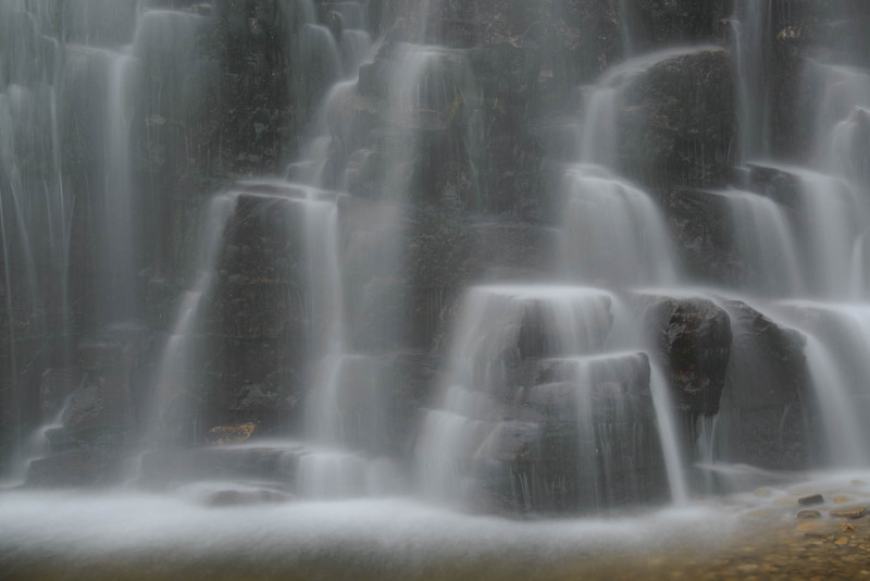 Mehrstufiger Wasserfall fließt über Felsen in Norwegen.