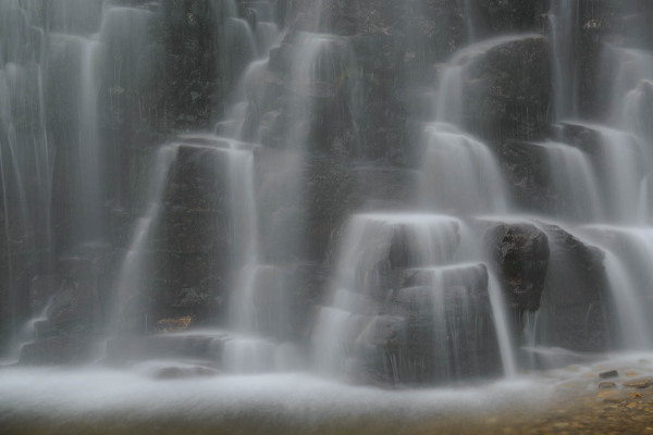Mehrstufiger Wasserfall fließt über Felsen in Norwegen.