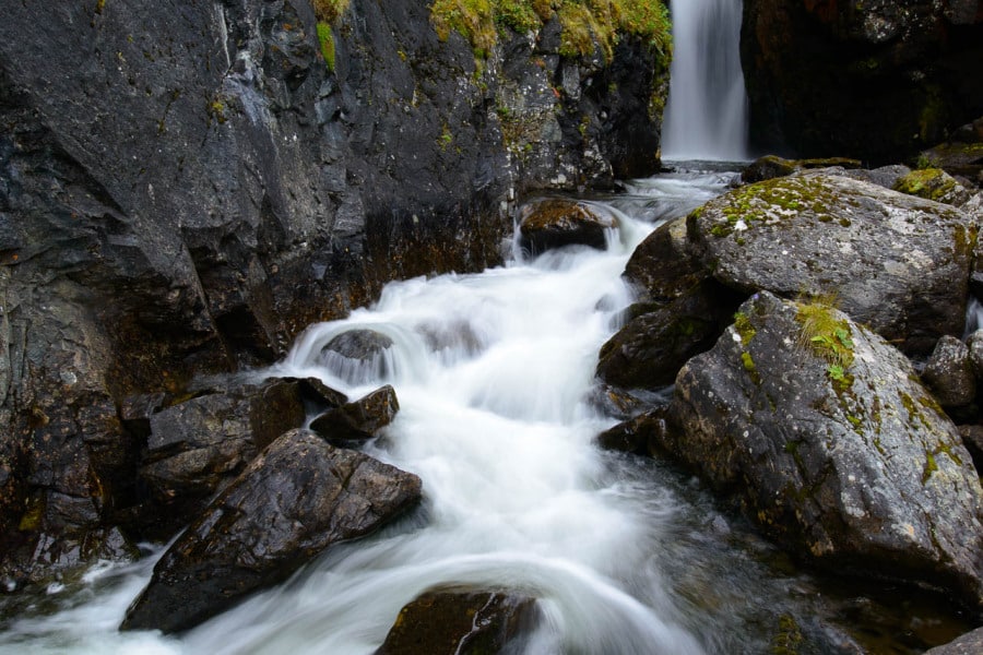 Ein Gebirgsbach fließt über Felsen zu einem Wasserfall in Norwegen.