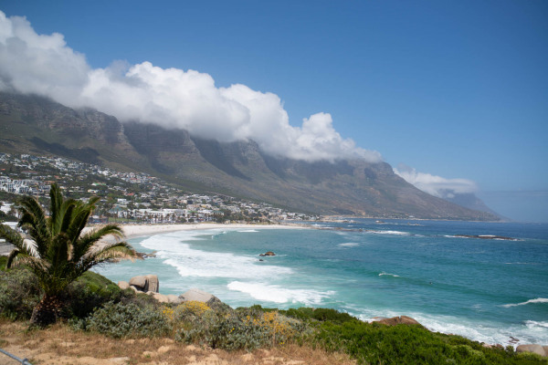 Küstenlandschaft in Südafrika mit Bergen, Wolken und Meer.
