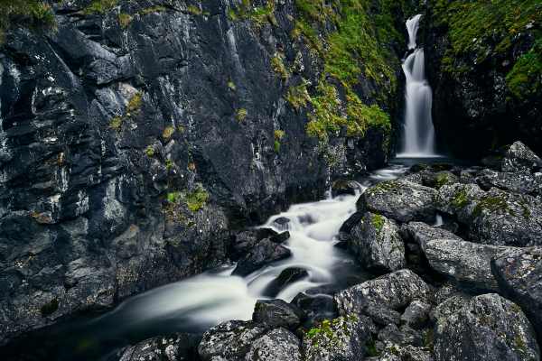 Rauschender Wasserfall im Dovrefjell-Gebirge mit Moos bewachsenen Felsen.