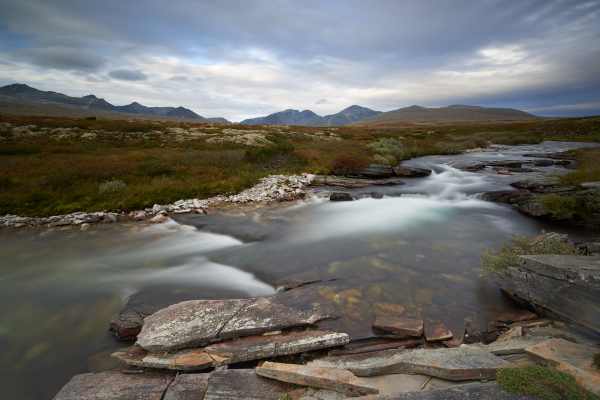 Ruhige Flusslandschaft im Rondane Nationalpark, umgeben von Bergen.