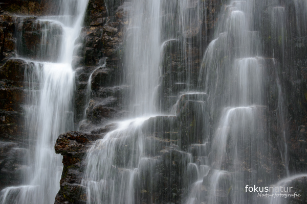 Kaskadierender Wasserfall fließt über dunkle Felsen