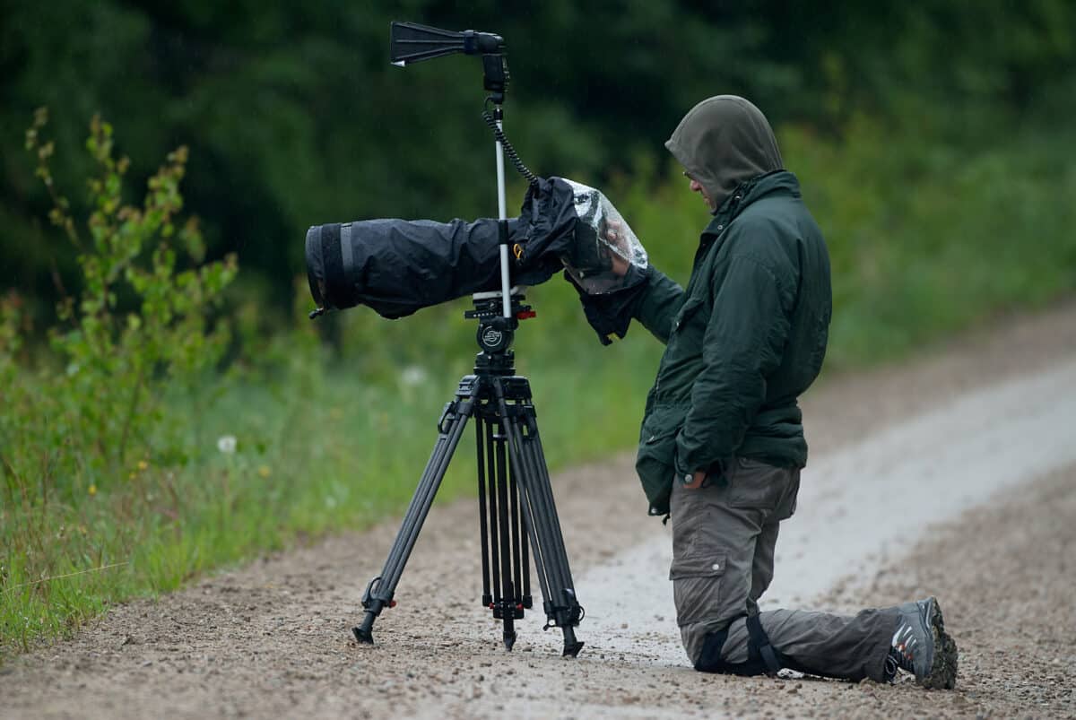 A nature photographer takes pictures in the rain, his camera is well protected.